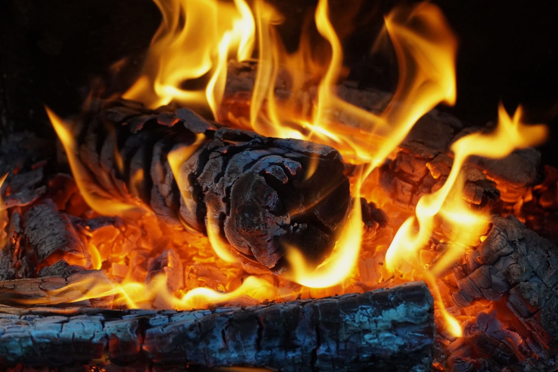 Detailed view of a blazing fire with vibrant flames and glowing embers, creating a warm and inviting atmosphere.